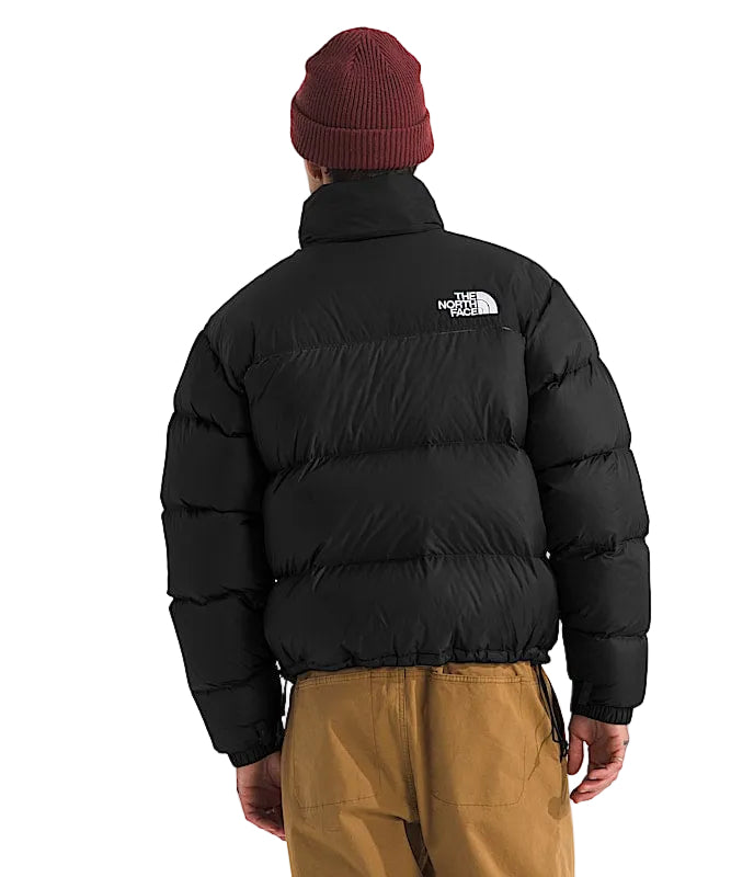 Person wearing a black puffer jacket with The North Face logo on the back, standing against a white background.