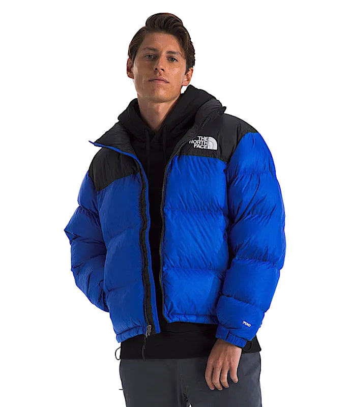 Person wearing a blue puffer jacket with The North Face logo on a white background