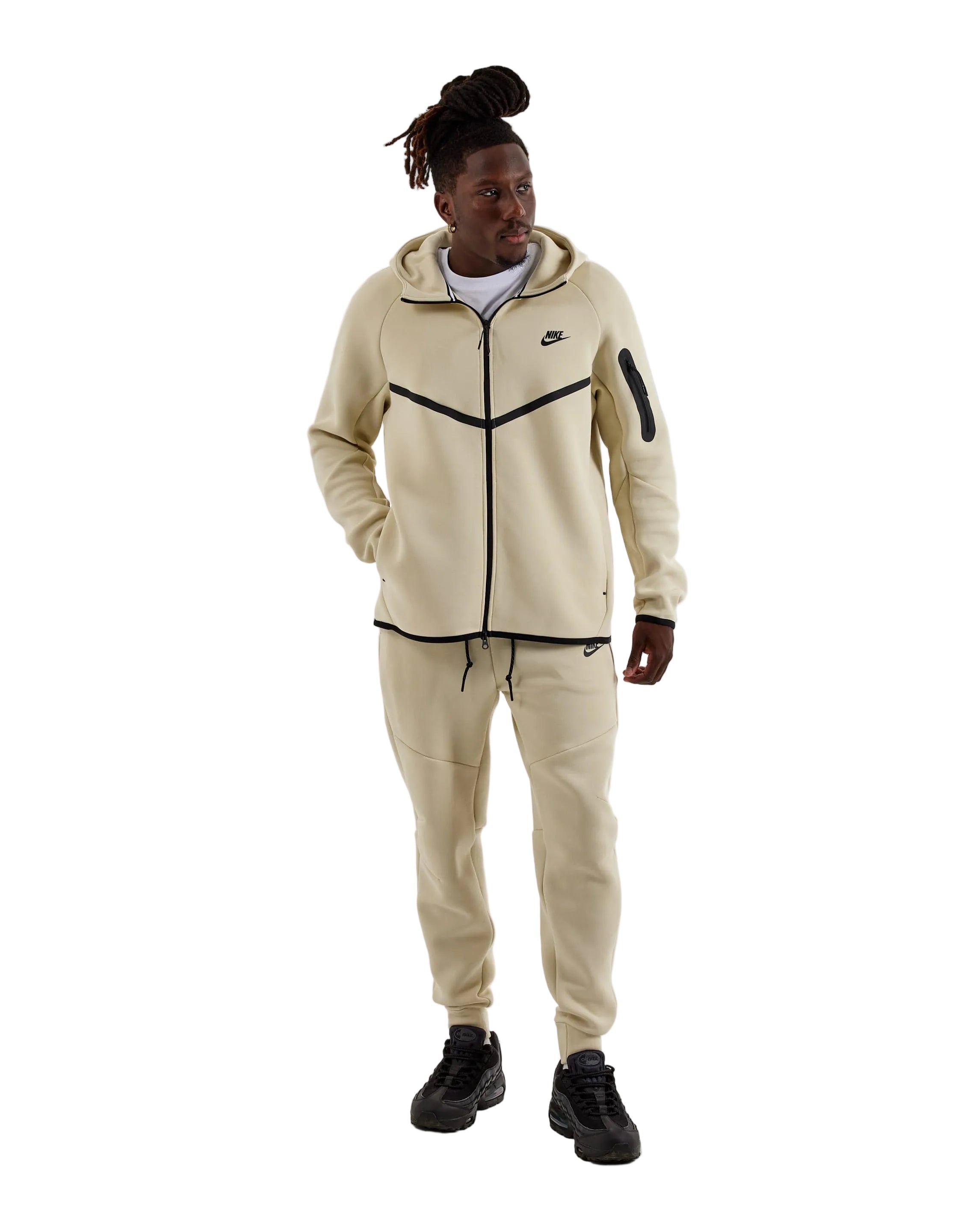 Person wearing a beige Nike tracksuit on a white background